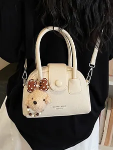 Elegante beige getextureerde handtas met pluche berenbedeltje en verstelbare schouderriem