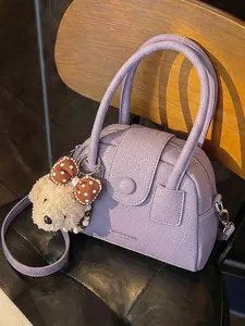Elegante paarse handtas met textuur, pluche bedeltje en een verstelbare riem.