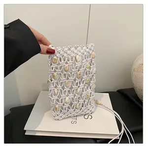 Vista detallada del bolso para móvil de macramé blanco hecho a mano con cuentas