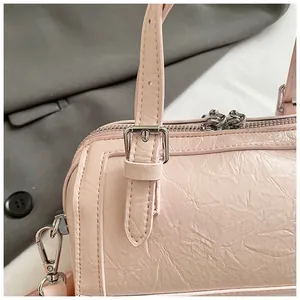 Close-up detail of a pink crinkled leather Boston bag featuring elegant silver buckles