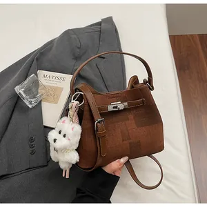 Elegante braune strukturierte Eimertasche mit Lederriemen und Hund-Schlüsselanhänger.