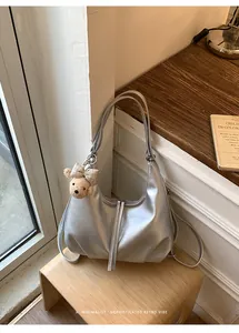 Borsa zaino convertibile argento con ciondolo a forma di orso su uno sgabello di legno