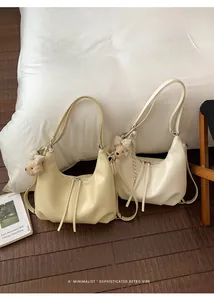 Coppia di borse a tracolla minimaliste beige e gialle disposte sul pavimento in legno.