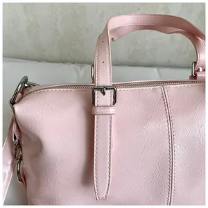 Détail d'un sac polochon rose vintage en similicuir texturé avec des ferrures argentées