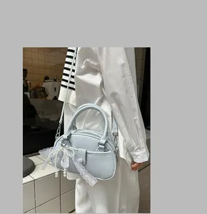 Elegant light blue small handbag with lace and pearl charms shown on a model's shoulder