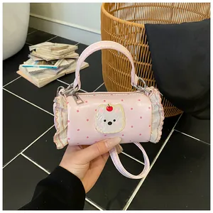 Detailed close-up view of a mini pink cylinder handbag with cute bear charm and ruffle edges
