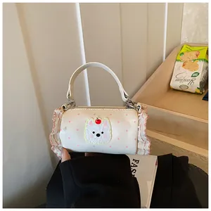 Close-up of a mini cylindrical handbag with pink polka dots and ruffles, held in hand.