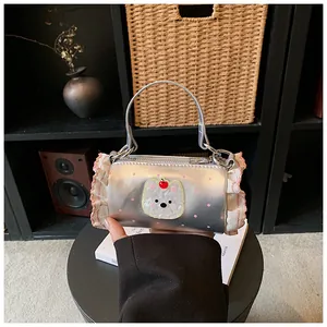 Fashionable mini silver cylindrical handbag with pink ruffles and a cute bear patch detail