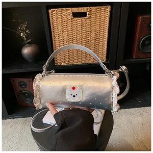 Close-up of silver cylinder handbag with cute bear patch and ruffle trim.