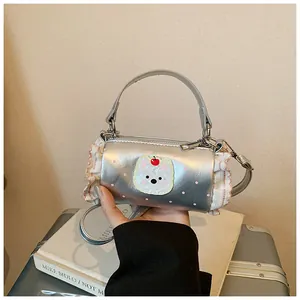 Close-up detail of a silver mini barrel handbag featuring a cute cartoon bear and pink lace trim.
