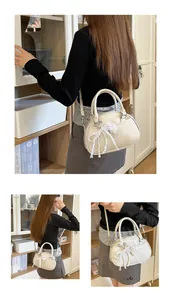 Sophisticated cream-colored handheld bag with delicate lace bow and pearl charms detail