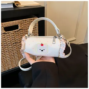 Detail view of a mini cylindrical white handbag with pink polka dots and a bear patch