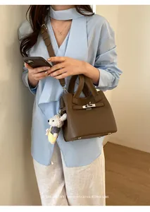 Elegant brown leather top-handle bucket bag with silver buckle and crossbody strap