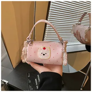 Detail view of pink polka dot barrel bag with cute bear patch and lace ruffle trim