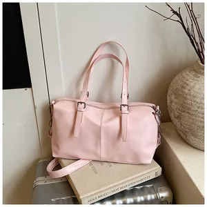 Détail d'un sac à main rose vintage posé sur une valise avec des livres