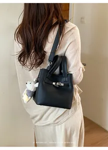 Elegant black textured leather bucket bag with silver buckle and cute white bear charm