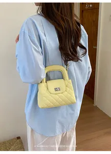 Close-up detail of a yellow quilted chain crossbody bag styled with a light blue shirt