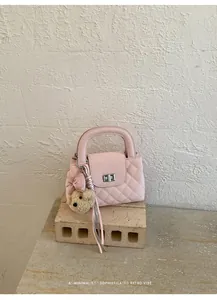 Small pink quilted crossbody handbag featuring a teddy bear charm and silver chain.