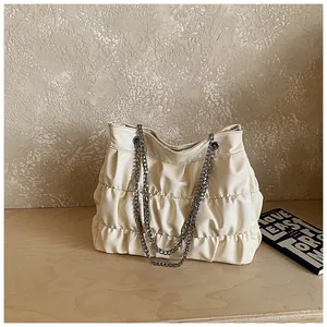 Detailed view of cream ruched leather tote bag featuring elegant silver chain straps