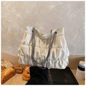 Creamy white pleated tote bag with silver chain straps in a lifestyle cafe setting