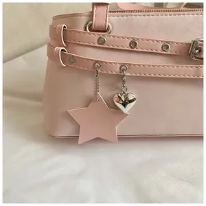 Close-up detail of a stylish pink underarm bag with silver heart and leather star charms