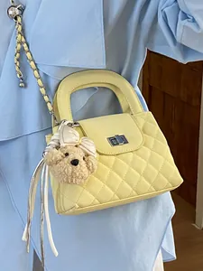 Elegant yellow quilted handbag with silver chain strap and a cute teddy bear charm
