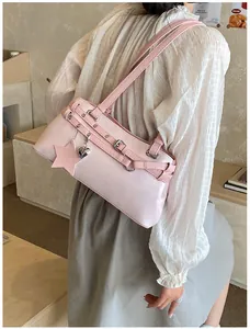 Detail view of a stylish pink shoulder bag with buckle design and star charm on a model