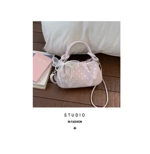 Detail view of pink polka-dot dumpling bag with decorative pearl bow accessory