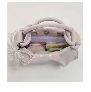 Top view of pink polka dot dumpling bag showing interior with phone and cosmetics