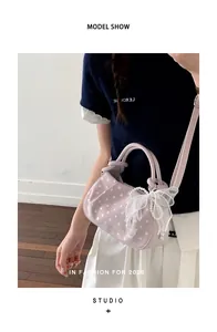 Detailed view of pink polka dot dumpling bag with pearl chain and lace bow accessory