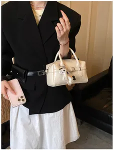Stylish cream Boston pillow bag for women with decorative buckle and cute dog charm.