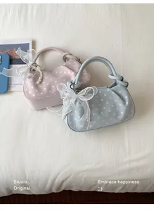 Detailed view of pink and blue polka-dot dumpling bags with lace bows and pearls.
