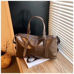 Vue détaillée du sac à main rétro en cuir brillant marron sur une surface en bois.