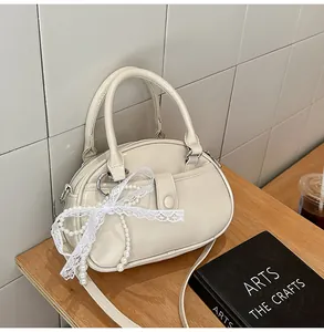 Elegant off-white patent leather handbag with decorative lace and pearl bow accent