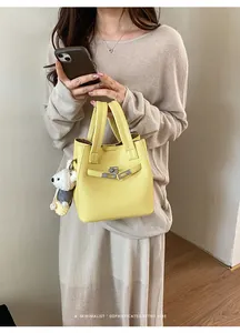 Detailed shot of a yellow pebbled leather bucket bag featuring a cute teddy bear charm