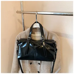 Sac polochon vintage noir brillant suspendu sur un portant à vêtements en métal chic