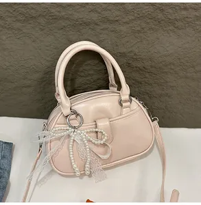 Elegant pale pink handbag with pearl bow and lace detail presented on a white surface.
