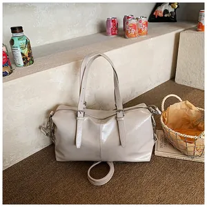 Détail d'un sac à main rétro beige brillant avec des lanières à boucles argentées.