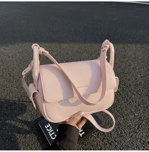Nahaufnahme einer rosa Umhängetasche aus strukturiertem Leder auf asphaltiertem Boden.