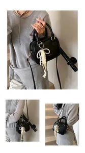 Close-up view of an elegant black quilted crossbody handbag with a pearl bow charm