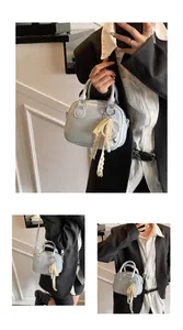 Detailed view of light blue women's handbag featuring a decorative lace and pearl charm
