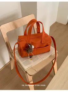 Lifestyle shot of a bright orange pebbled leather pillow bag on a wooden chair.