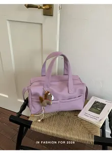 Lavender purple pebbled leather pillow bag with a cute horse keychain on a woven chair