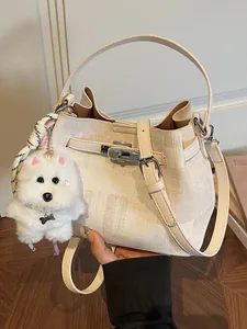 Elegante cremefarbene Pendler-Eimertasche mit einem niedlichen weißen Plüschhund-Anhänger