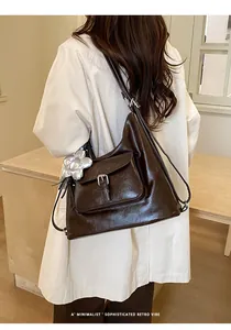 Detail of large dark brown retro hobo bag featuring front buckle pocket and silver flower charm