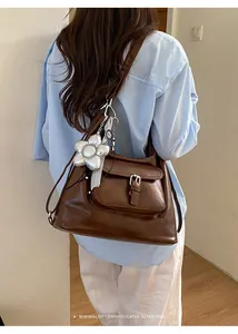 Detail view of a large brown leather tote bag worn by a model in a casual setting