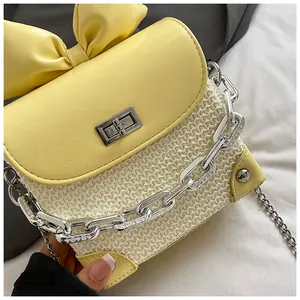 Detail view of a yellow bow mini crossbody bag featuring a chunky silver-tone chain strap.