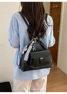 Close-up detail of a minimalist black faux leather backpack with silver charms