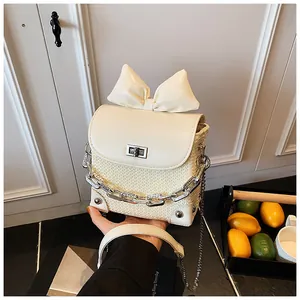 Detailed view of elegant cream mini bow bag featuring woven texture and silver chain strap