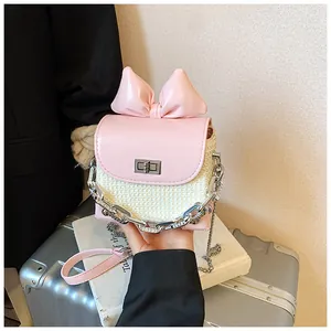 Close-up of pink bow mini crossbody bag featuring a unique woven straw texture and chain.